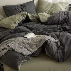 an unmade bed with pillows and blankets on it