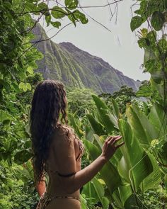 a woman standing in the jungle looking at plants