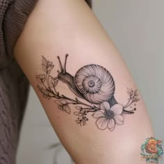 a snail and flower tattoo on the arm