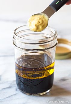 a spoon with some food in it on top of a glass jar filled with liquid