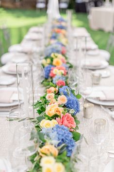 a long table is set with flowers and plates