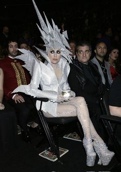 a woman dressed as the white queen sitting in a chair with her legs spread out