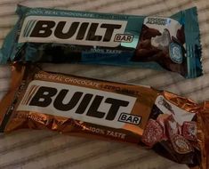 two chocolate bars sitting on top of a bed next to each other with the word built written on them