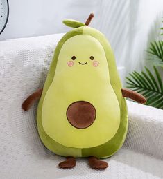 a stuffed avocado sitting on top of a white couch next to a clock