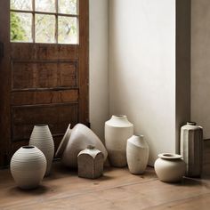 there are many vases sitting on the floor in front of a door and window