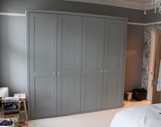 a bedroom with gray cabinets and white sheets