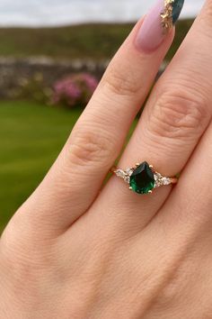 a close up of a person's hand with a ring on their finger and an emerald colored manicure