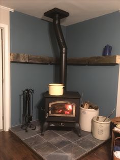 a wood burning stove sitting on top of a tile floor next to a shelf filled with pots and pans