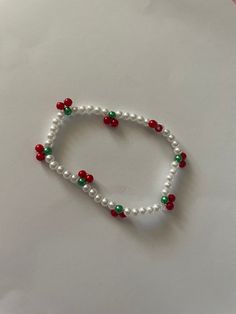 a white beaded bracelet with red, green and white beads is on a table