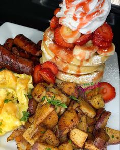 a white plate topped with pancakes, eggs and sausages next to other breakfast foods