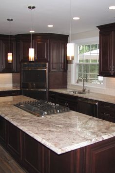 a kitchen with marble counter tops and dark wood cabinets