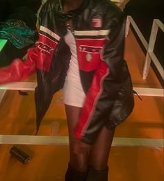 a woman in black and red leather jacket standing next to a table with an umbrella