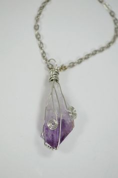 Each Amethyst necklace is carefully hand wrapped with silver plated copper wire and is suspended from a stainless chain. Pendant measures approximately 1 1/2 inches in length. Each stone is cleansed, charged and blessed before shipping to maximize it fullest potential. NOTE: Item pictured is NOT the exact Item you will receive. All items in stock bear a close resemblance to the item pictured, but because these are natural stones, the size, shape and color will slightly vary for the item purchase Silver Hand Wrapped Metal Necklace, Purple Wire Wrapped Metal Jewelry, Spiritual Purple Wire Wrapped Necklace, Amethyst Wire Wrapped Necklace Gift, Spiritual Hand-wrapped Silver Necklaces, Spiritual Hand Wrapped Silver Necklace, Wire Wrapped Crystal Pendant Necklace In Metal, Purple Amethyst Wire Wrapped Necklaces, Purple Amethyst Wire Wrapped Necklace