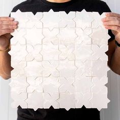 a man holding up a white tile pattern