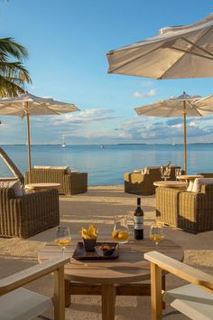 an outdoor dining area with chairs and umbrellas on the beach next to the ocean