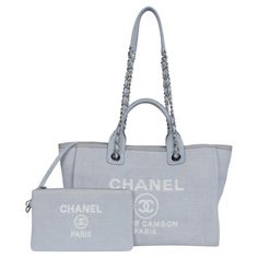 Authentic, pre-loved Chanel Deauville shoulder bag tote. Features baby blue canvas, silver-tone hardware, leather handles with dual shoulder straps with chain-link and blue trim, white embroidered logo embellishment at front face, tonal canvas lining, and two pockets on interior walls along with a zipper top closure. Authenticity RFID: JHP3913G Made in Italy Strap drop: 14" 12.5"L x 6"W x 9.5"H Condition Gently Used This is a beautiful Chanel! light signs of use and corner color change, the inte Baby Tote Bag, Chanel Cambon, Chanel Tote, Front Face, Chanel Vintage, Blue Trim, Blue Canvas, Bag Packaging, Zipper Top