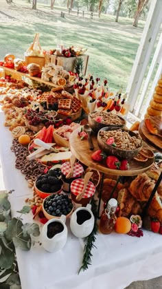 a table filled with lots of food on top of a white cloth covered tablecloth