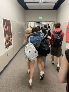 several people walking down a hallway with backpacks on their back and one person holding onto another