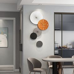 there are three clocks on the wall in this dining room, one is orange and the other is grey