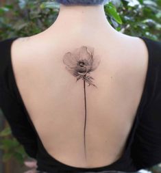 the back of a woman's neck with a single flower tattoo on her left shoulder