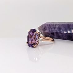 an amethorate and diamond ring sitting next to a rock