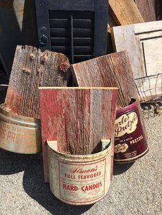 three old tins are sitting next to each other on the ground, one has been turned into a candle holder