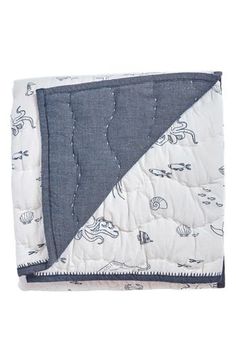 a blue and white quilted blanket with an elephant design on the bottom, in front of a white background