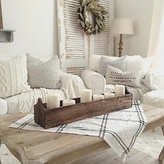 a living room filled with white furniture and pillows on top of a wooden coffee table