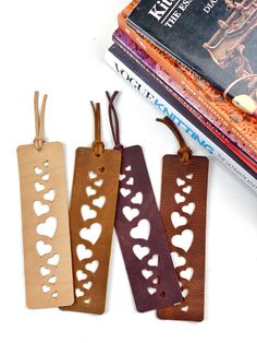 three bookmarks with hearts cut out of them sitting next to a stack of books