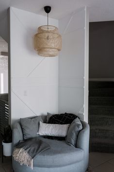 a living room filled with furniture and a lamp hanging from the ceiling next to a wall