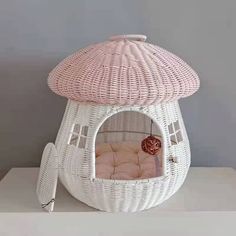 a white wicker dog house with a pink cushion