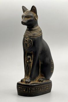 an egyptian cat figurine is shown in black and gold colors on a white background