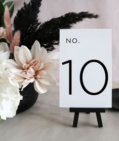 there is a sign with the number ten on it next to some flowers and feathers