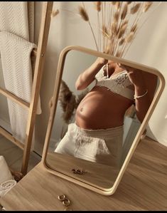 a woman's stomach is seen in the reflection of a mirror with gold rings on it