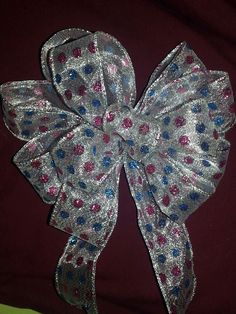 a large silver bow with red, blue and pink flowers on it's side