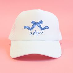 a white hat with a blue bow on it that says adpi against a pink background