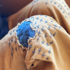 an old piece of cloth with blue crosses on it is sitting on a bed and the fabric has been torn off