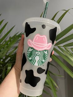 a starbucks cup with a cow print on it and a straw in the top is being held by a hand