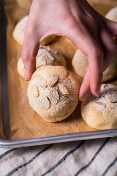 a person placing powdered sugar on top of pastries in a baking pan,