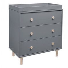 a grey dresser with three drawers and two wooden legs on the bottom, in front of a white background