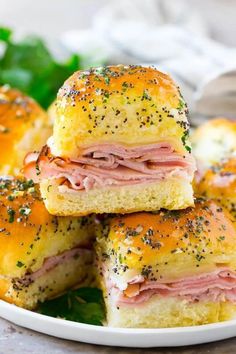 ham and cheese sliders stacked on top of each other in a white plate with greens