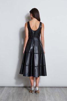 Meet our modern, endlessly versatile Fit & Flare Dress in luxe Vegan Leather that's infused with a chic vibe. The feminine self-belt & tiered midi skirt give it the cool factor whether worn with pumps or dressed up with strappy heels for night. Vegan Leather Belted Midi Fit & Flare Dress 100% Polyester Runs true to Size Model is 5'9" and wearing size 2 Dry Clean Only Imported Style #: ETR44228 Leather Midi Dress For Work, Leather Midi Dress For Night Out, Fitted Midi Dress For Formal Occasions, Fitted Formal Midi Dress, Leather Belted Dresses For Parties, Luxury Knee-length Spring Midi Dress, Fall Evening Midi Dress, Luxury Knee-length Midi Dress For Spring, Chic Black Midi Dress