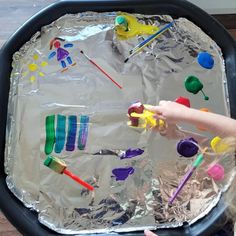 a child is playing with an art project on tin foil