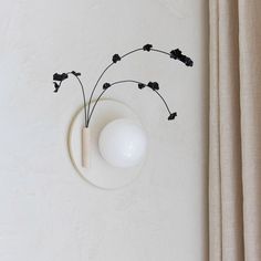 a white vase sitting on top of a table next to a wall mounted light fixture