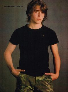 a young man in black shirt and camo shorts standing with his hands on his hips