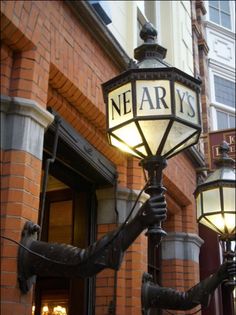 a lamp post with the word ne arys written on it in front of a brick building