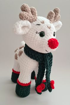 a knitted white reindeer with red nose and green scarf