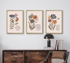 three framed art prints on the wall above a dresser with a chair and bookcase