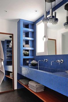 a bathroom with blue tiles on the walls and counter tops, along with two sinks