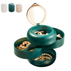 three green containers filled with jewelry on top of a white table next to two mirrors